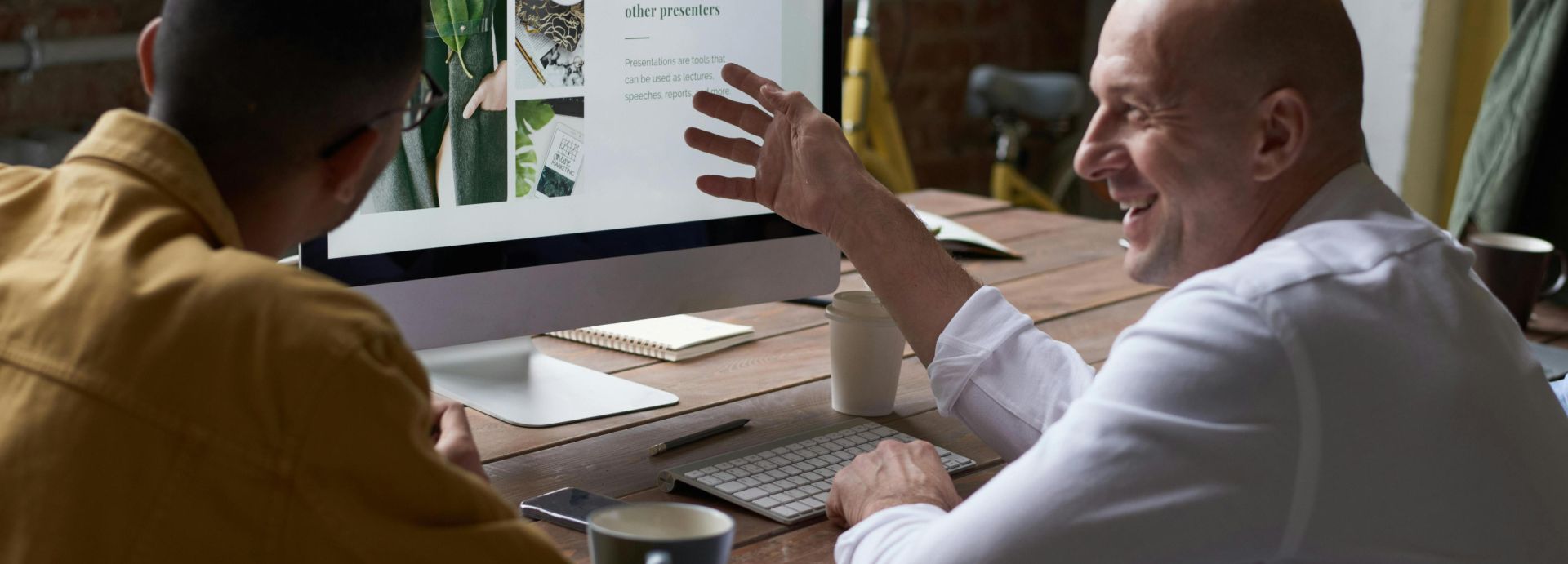 Two professionals collaborating in a modern workspace, discussing a project on a computer screen.