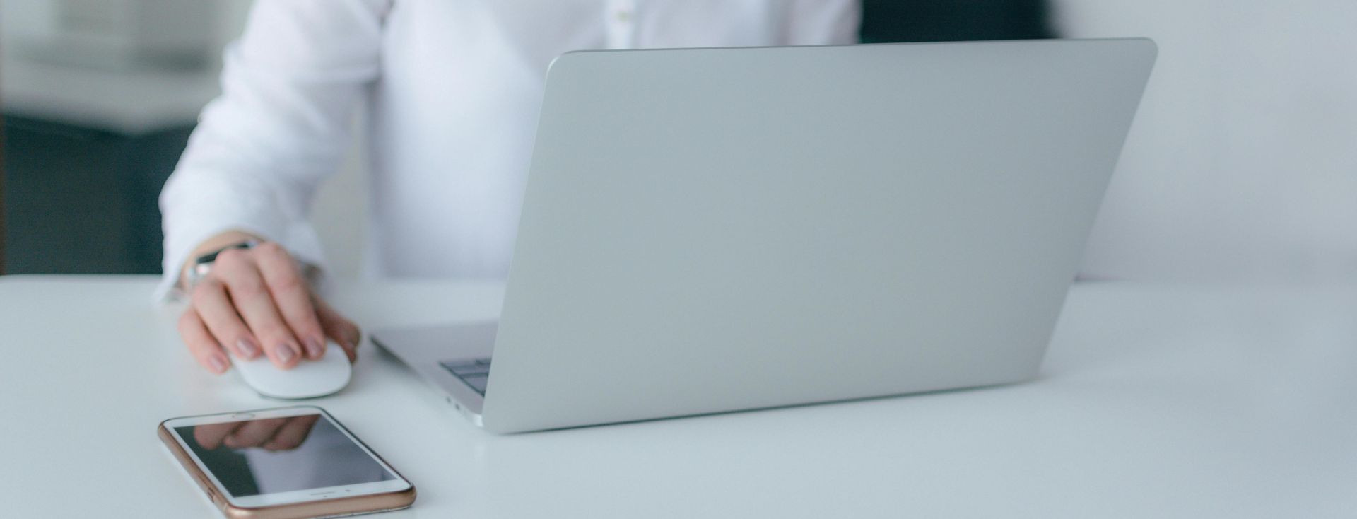 A woman working at a desk using a laptop and smartphone, exemplifying remote work.