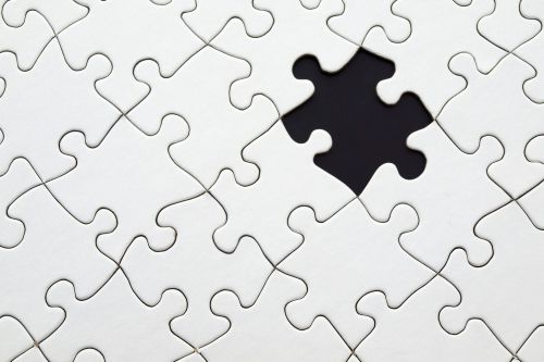 Close-up of an incomplete white puzzle with one missing piece, symbolizing challenge and strategy.
