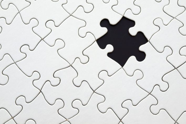Close-up of an incomplete white puzzle with one missing piece, symbolizing challenge and strategy.
