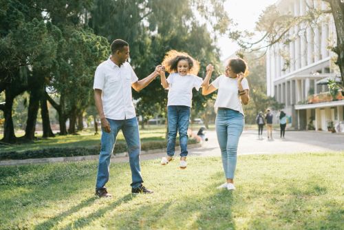 Joyful family enjoying a playful day at the park, embracing love and togetherness under the summer sun.