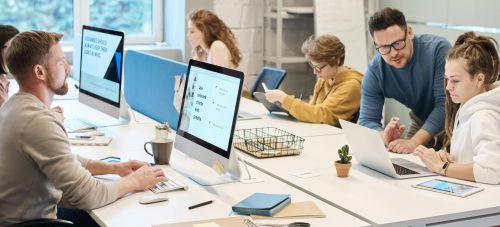 Team collaboration in a modern office setting with computers and diverse employees working together.